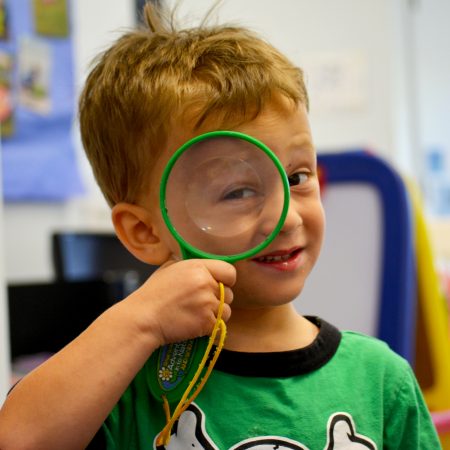 Brunette boy green shirt mag glass