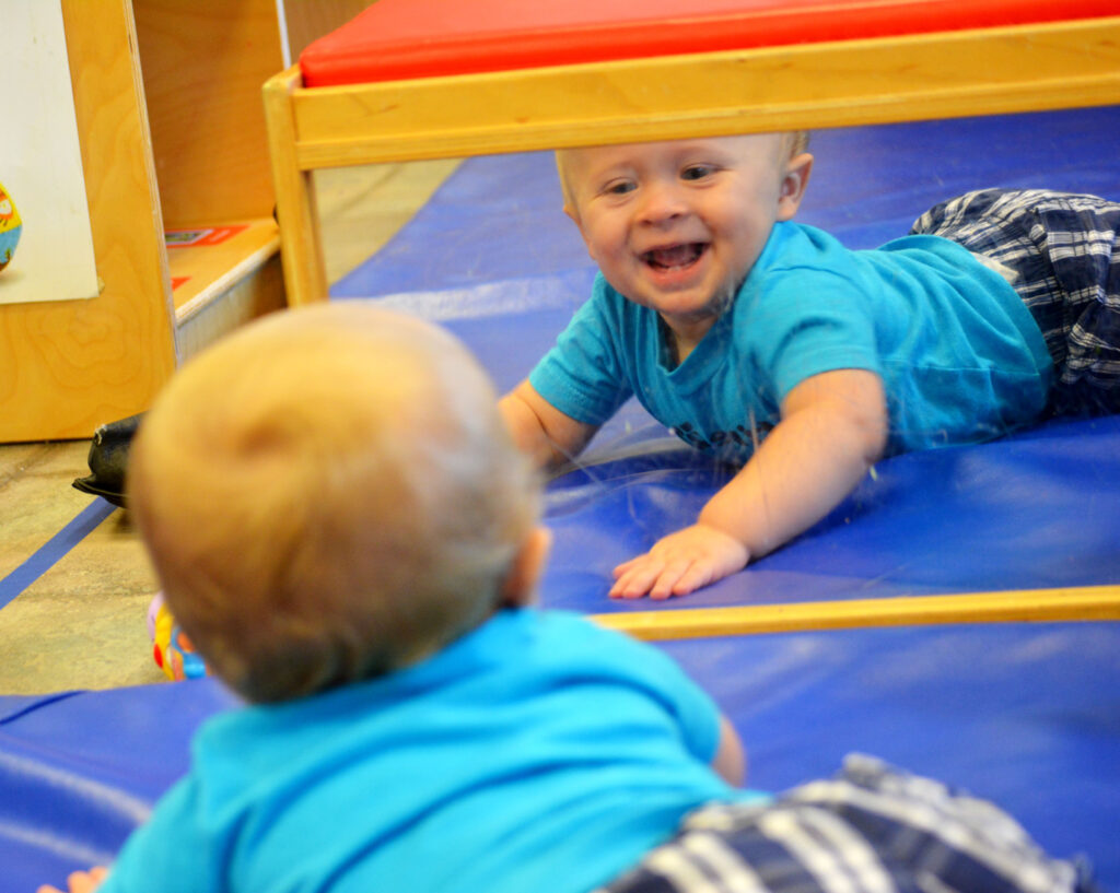 blonde baby laughing in the mirror