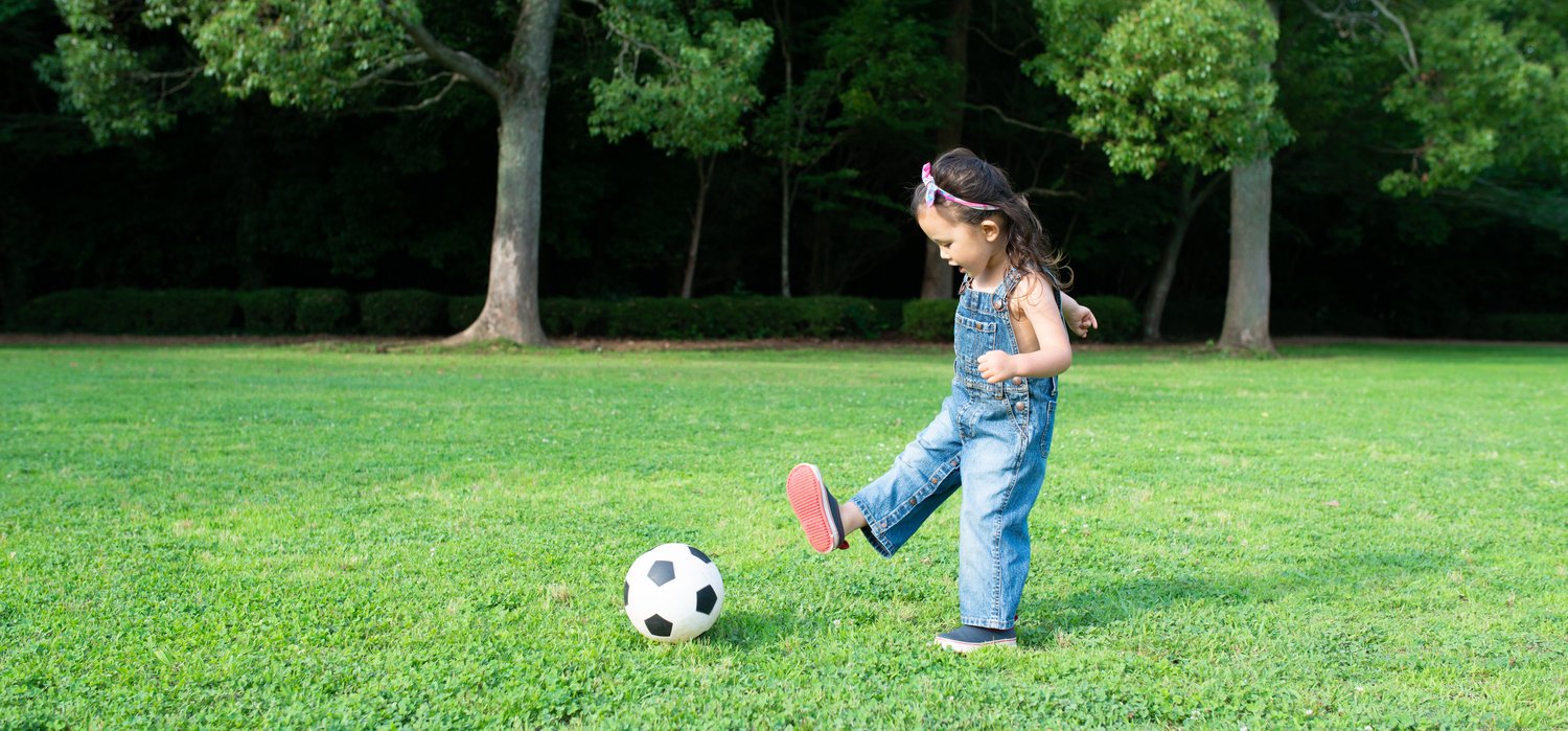Preschooler focused while playing soccer outdoors