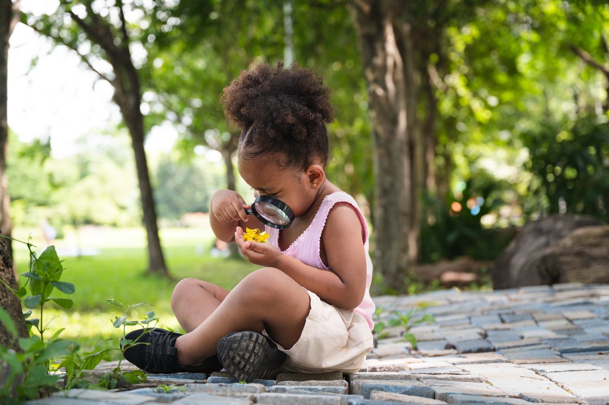 Preschooler focused outdoors with a magnifying glass