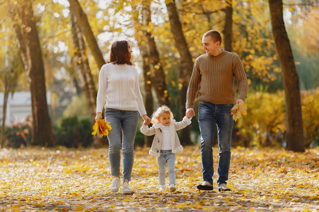 Happy family walking on a tree-lined alley in autumn park