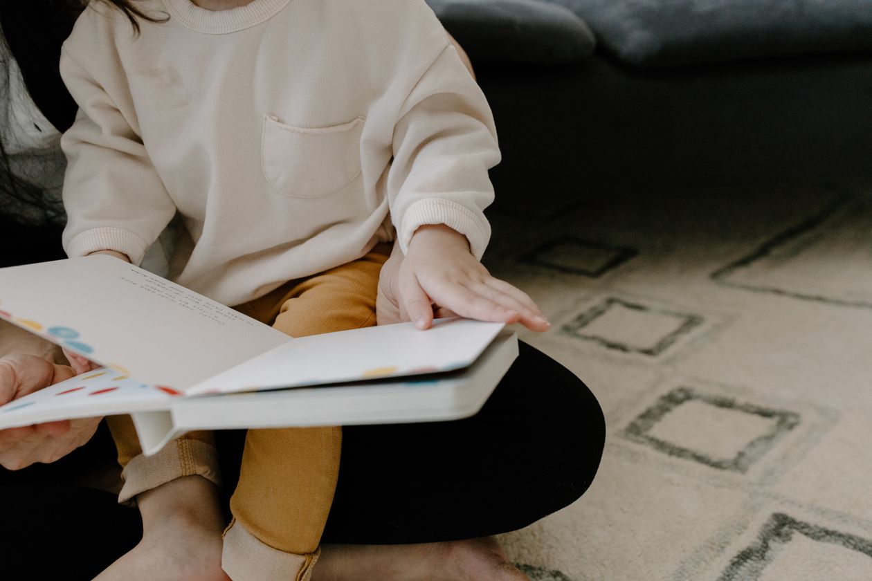 A child sitting on a person's lap holding a book