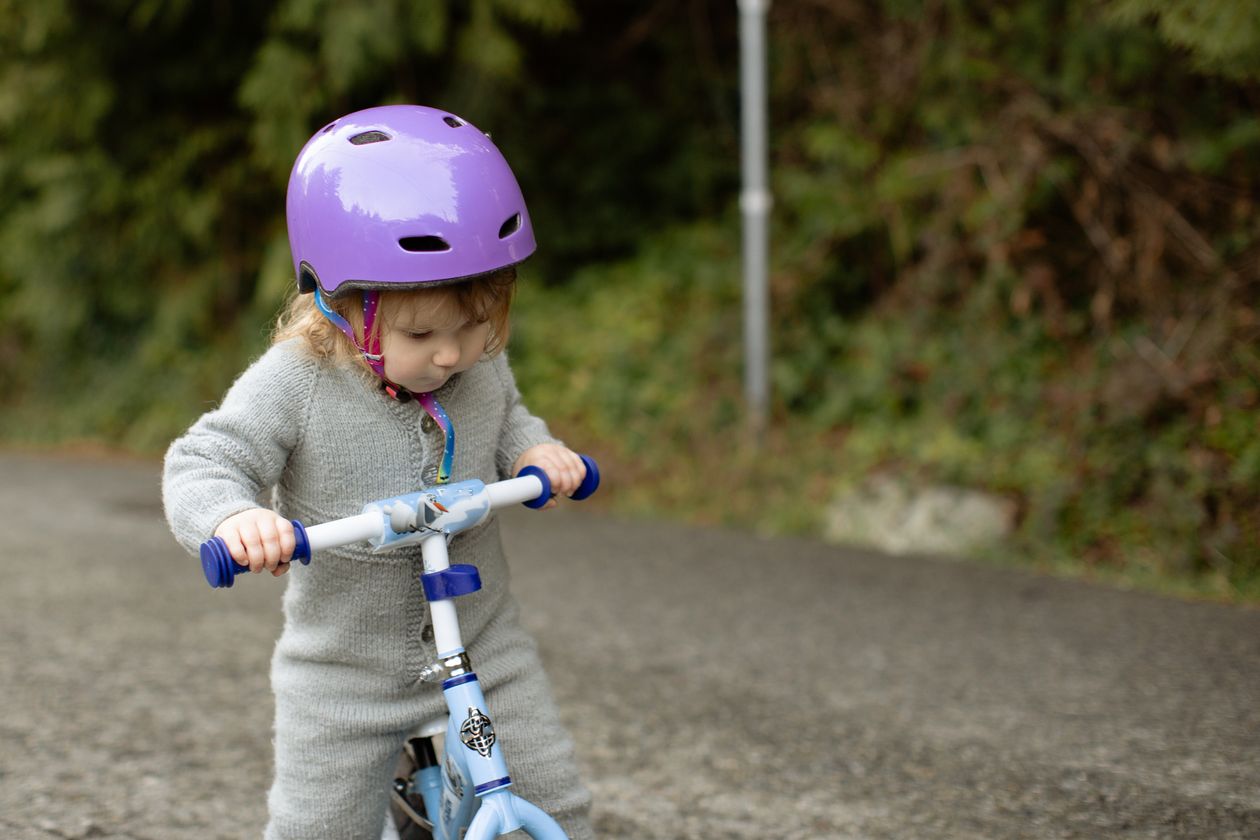 Focused little cyclist girl riding a runbike at countryside