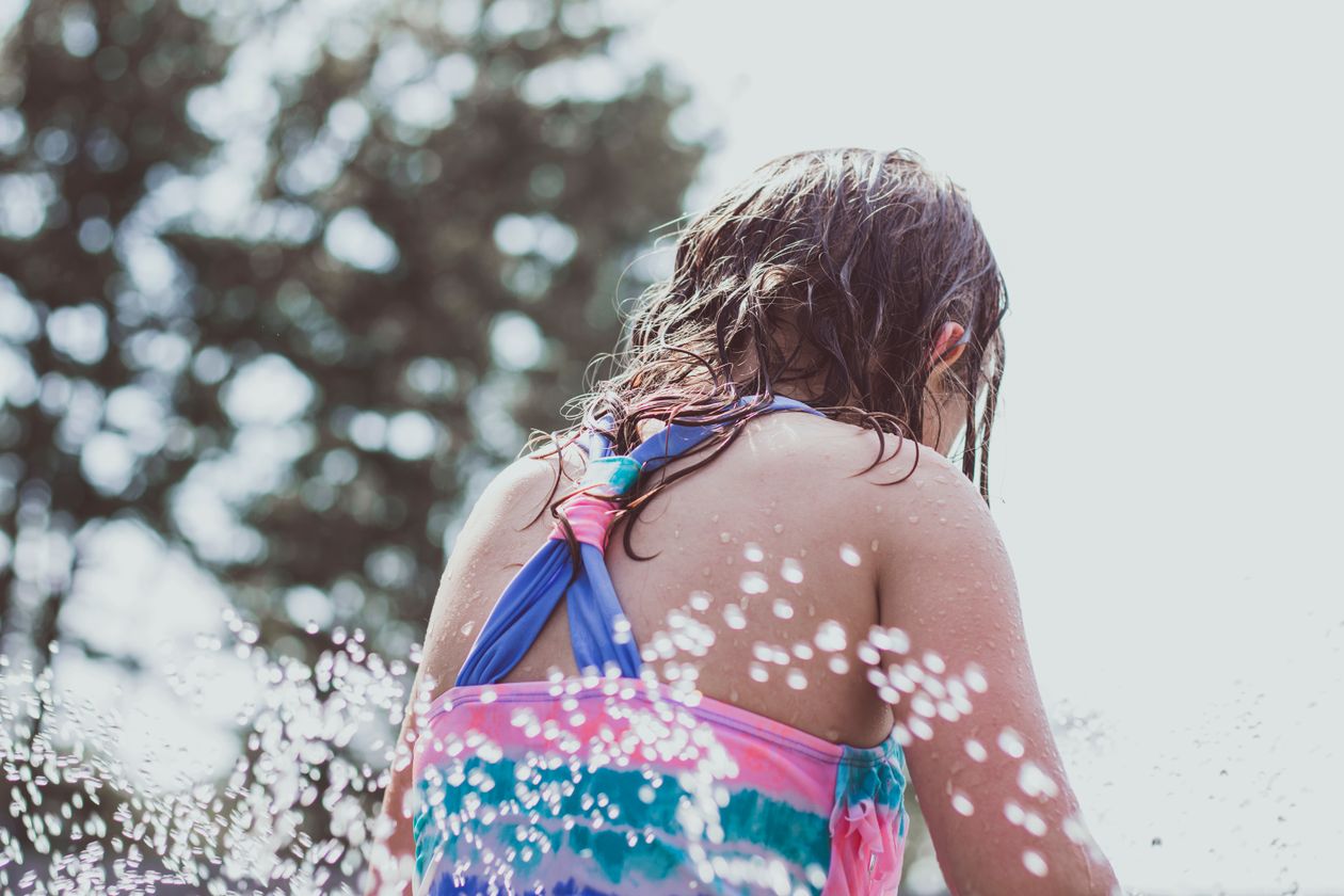 Back view of a girl in a swimming costume splashing water