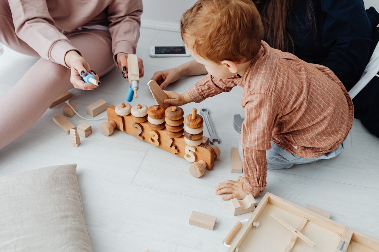 A young boy sitting on the floor while holding wooden toys