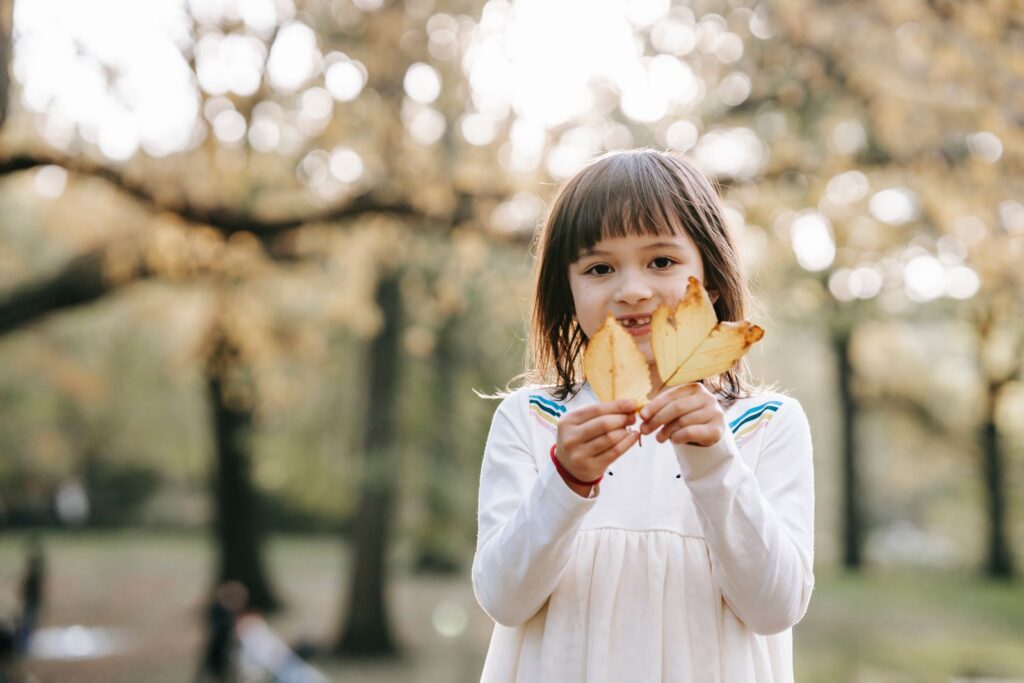 Preschool girl holding up yellow leaves on a fall walk at Southeastway Park