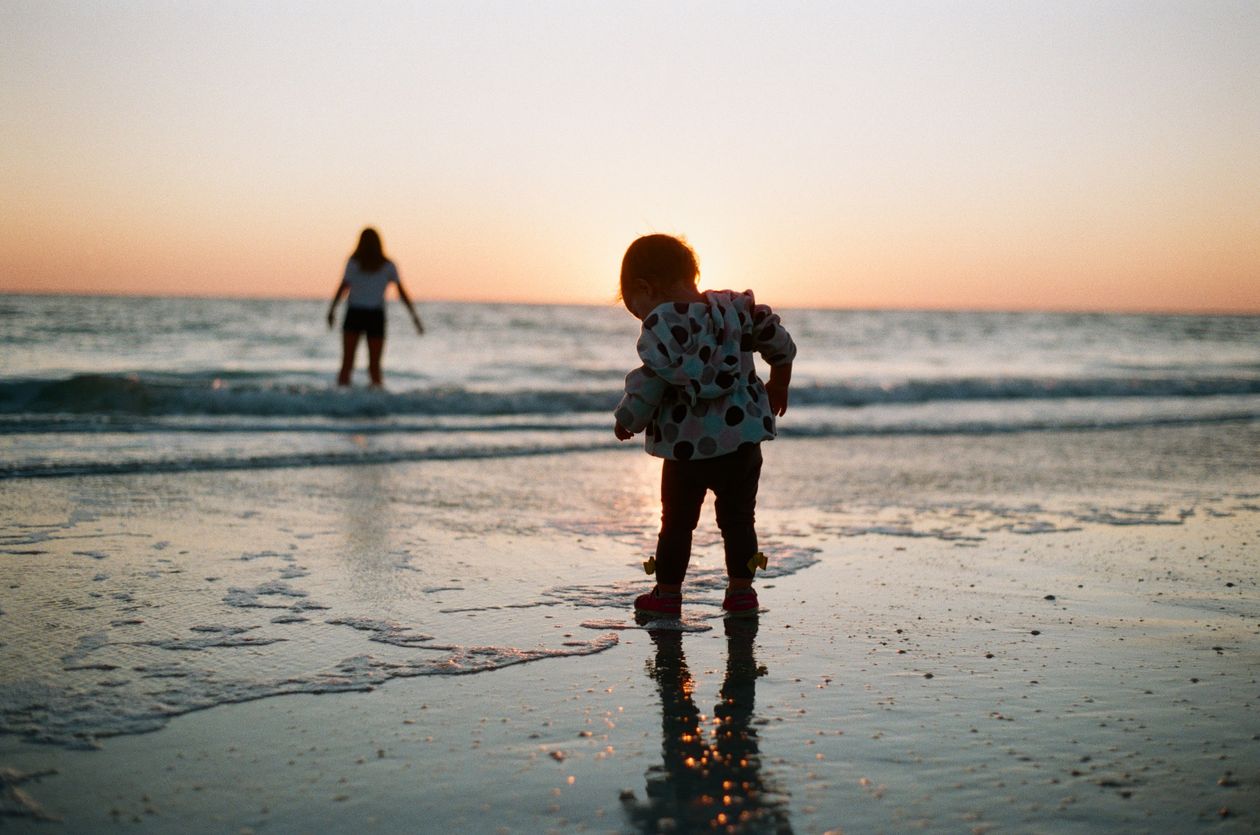 A child walking on the beach at sunset