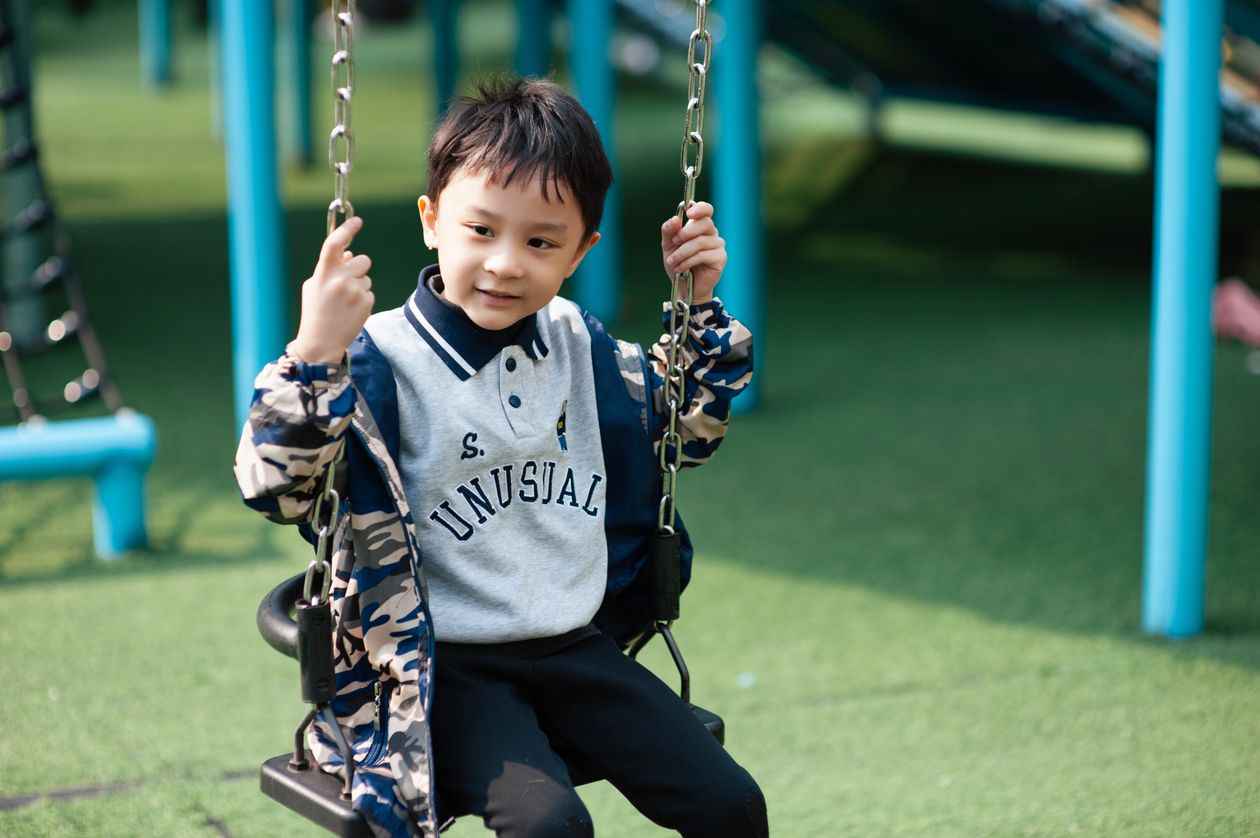 Young boy enjoying swing at outdoor playground