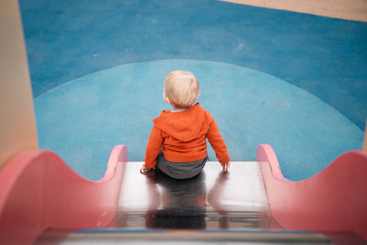 Little child playing on slide in playground