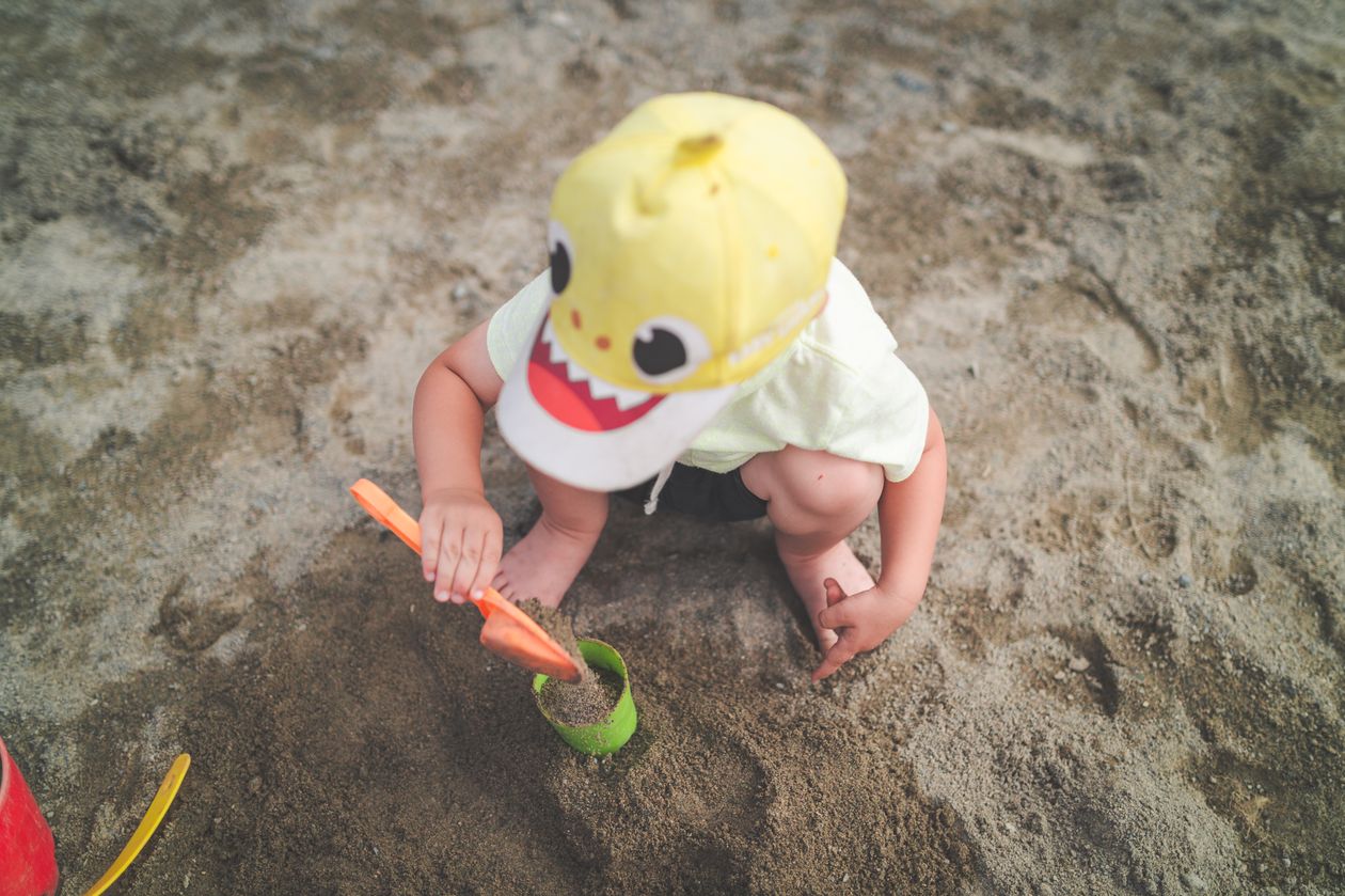A child shoveling sand at the beach