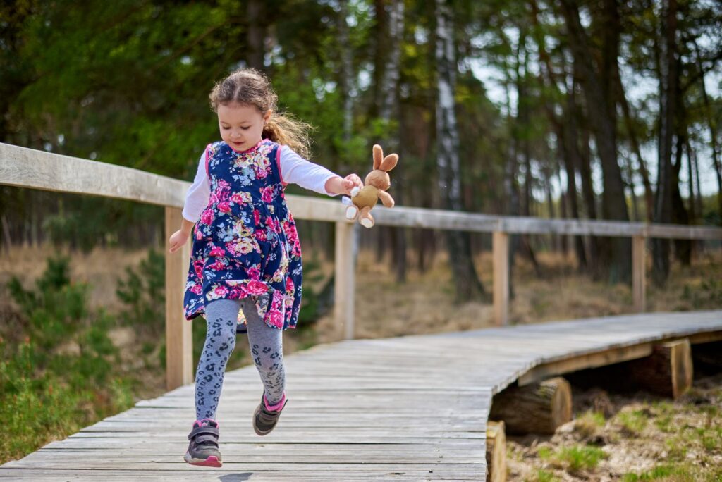 Preschool girl running along a wooden boardwalk through the woods at Black Hammock Wilderness Area