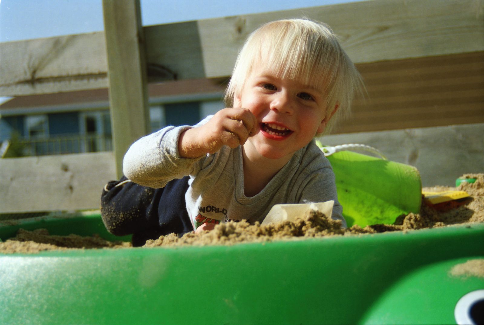 Smiling preschool boy playing in a sandbox, where early STEM skills show up in everyday play