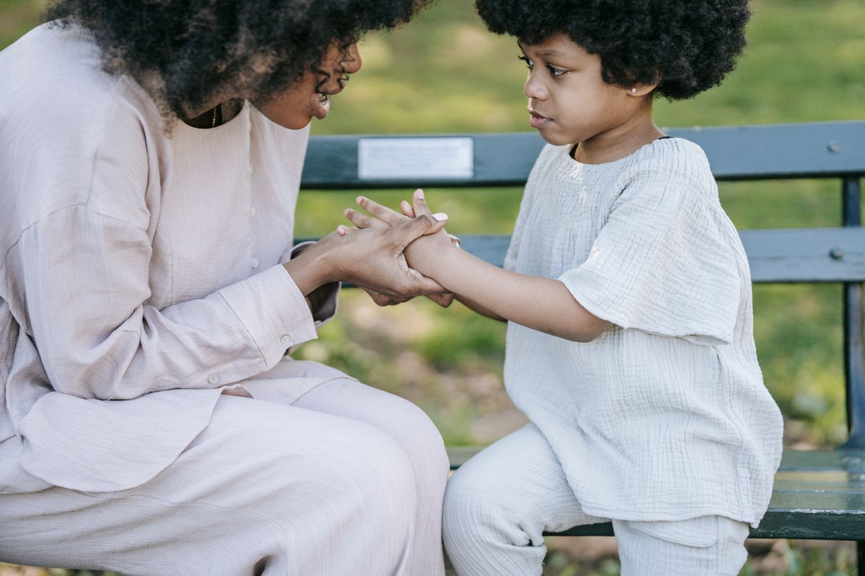 Woman talking to a girl while holding her hands