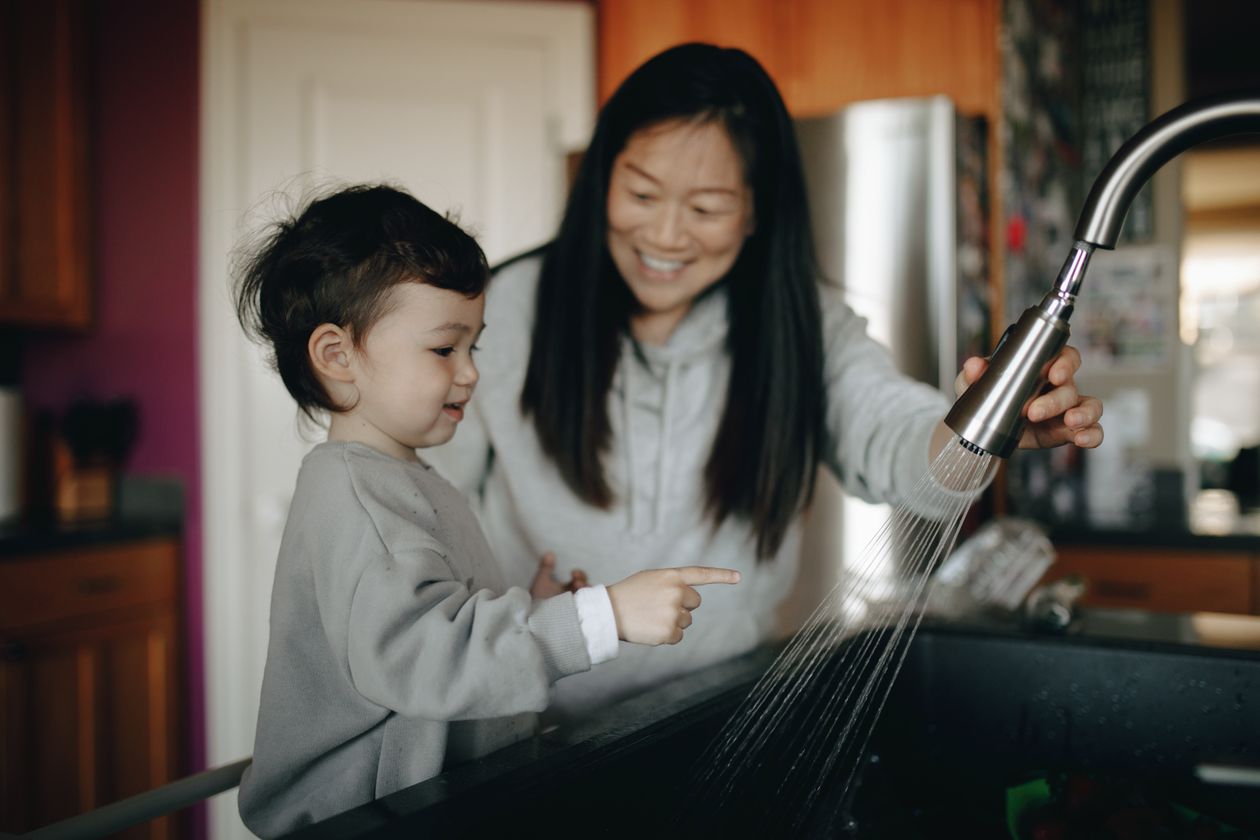 Mother and child standing in front of a kitchen sink