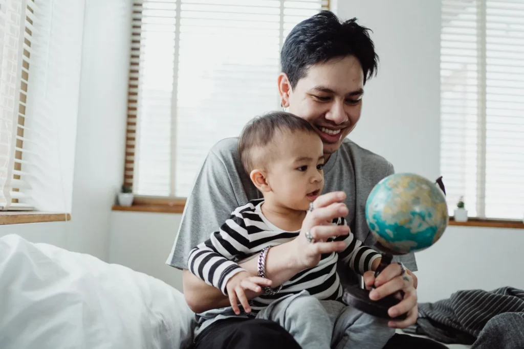 Dad and toddler sitting together by a window looking at a small globe