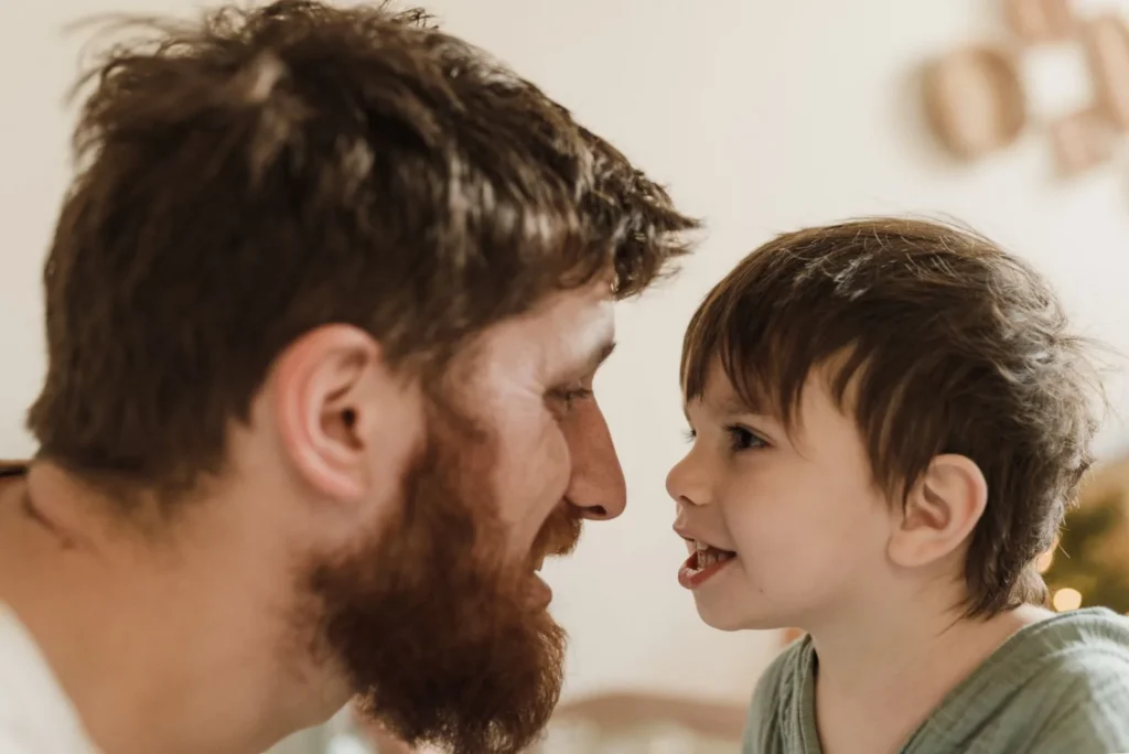 Dad and young son face to face, the boy smiling mid-conversation